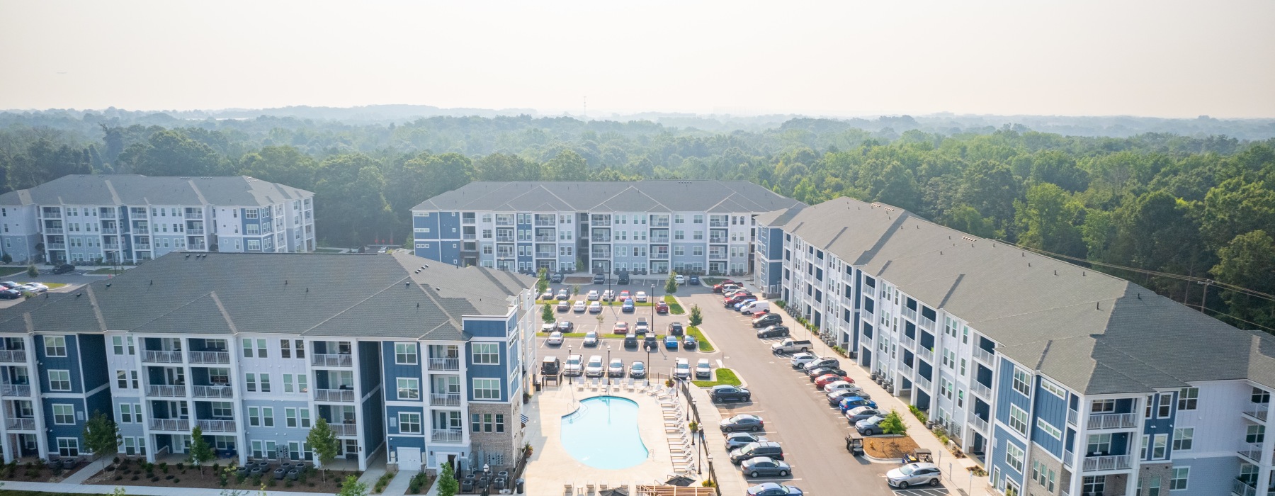Aerial view of an apartment complex with a central pool and surrounding parking